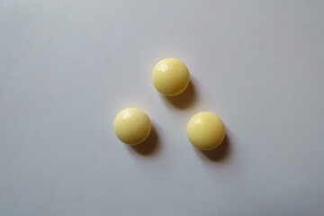 Three round yellow pills of xylitol from above