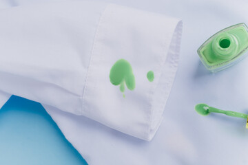 Green nail polish spilled on the sleeve of a white shirt
