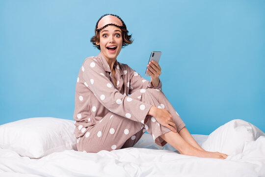 Full size photo of young happy excited crazy girl using smartphone lying on blanket isolated on blue color background