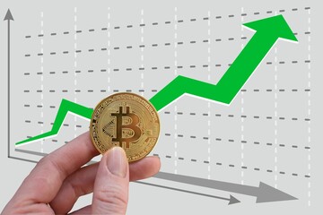 hand holds bitcoin on background of growing graph with green upward arrow. Exchange rate growth....