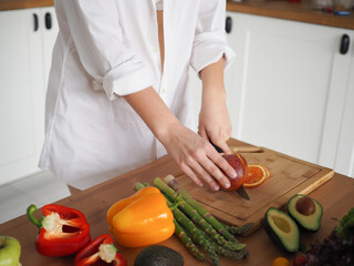 A young woman nutritionist prepares a delicious and healthy breakfast. Cuts salad, vitamins, vegetables and fruits