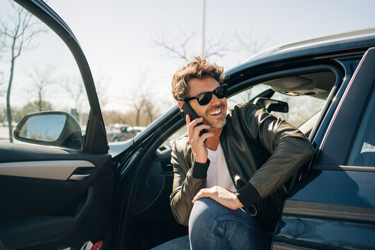 Cheerful man talking on smartphone in car