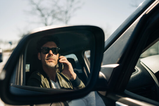 Driver reflecting in side mirror while talking on smartphone