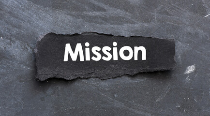 word MISSION on a black piece of paper laid over a black background.