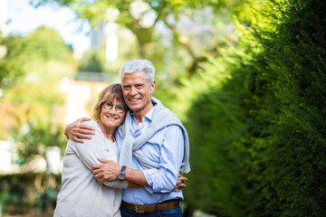 happy older couple holding each other in park