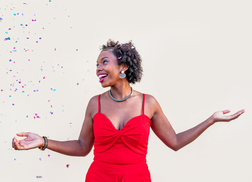 Happy African American woman standing under confetti during celebration