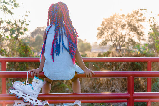 Unrecognizable Ethnic Girl With Roller Skates Contemplating White Sky