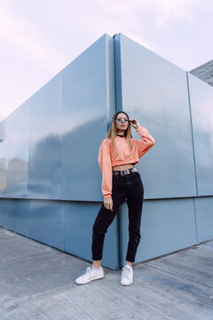 Stylish woman in sunglasses leaning on building wall