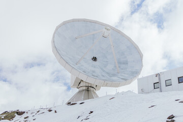 Observatory on snowy ridge against house exterior in ski resort