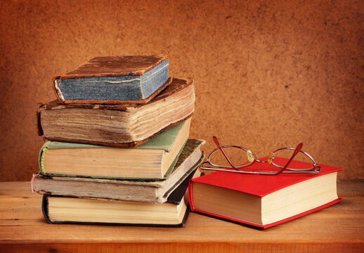 Stack of old books and glasses on wooden table