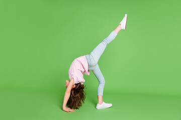 Full body profile side photo of young little girl stand bridge pose raise legs acrobat isolated over green color background - obrazy, fototapety, plakaty