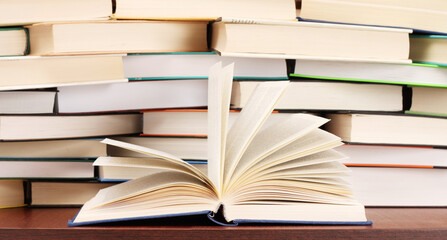 Stack of books and opened book on table