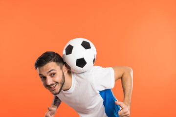 Football player do tricks with ball isolated on orange background