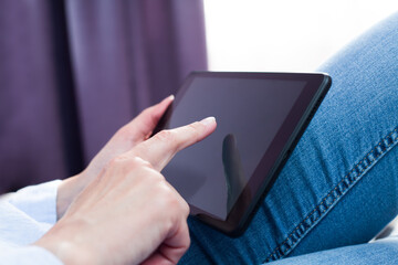 Female hands using digital tablet at home. Close-up.