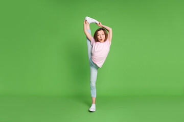 Full size photo of young little girl hold leg stretch split gym exercise sport isolated over green...