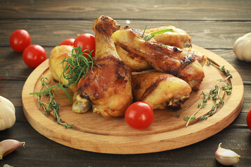Fried chicken legs with spices on the board on a wooden table.