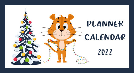 The cover of the Horizontal desktop calendar for 2022. The symbol of the year in the Chinese calendar. The Year of the Tiger. Tiger stands with a garland near the Christmas tree.