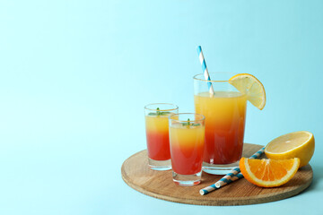 Board with Tequila sunrise cocktail on blue background