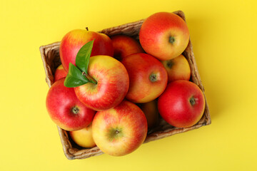 Basket with red apples on yellow background