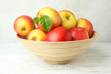 Bowl with red apples on white wooden table