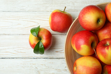 Bowl with red apples on white wooden table
