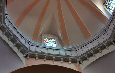 Cupola di una chiesa illuminata dal sole con ballatoio e finestra con vetrate artistiche