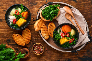 Chilean meat soup with pampkin, corn, fresh coriander and potatoes on old wooden table background. Cazuela. Latinamerican food.