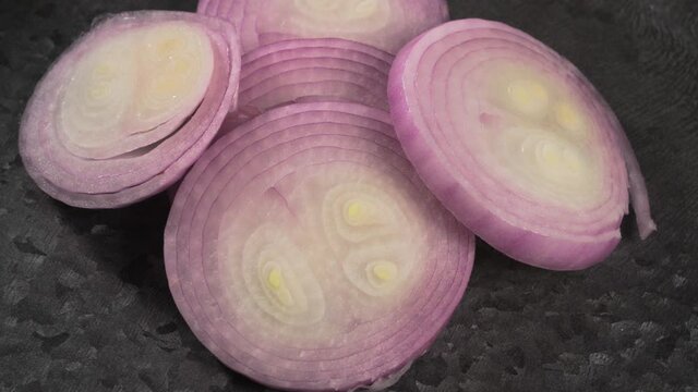Sliced red onion on metal plate rotation. Closeup top view.