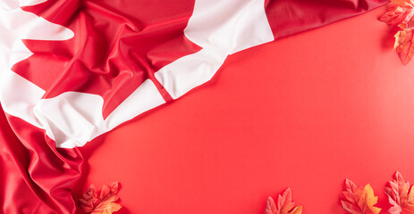 A beautiful Canada national flag cloth fabric with red silk maple leaves, a sign or symbol of Canada day concept on red background.