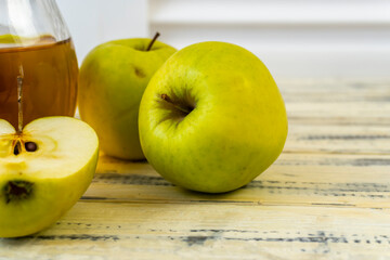 Green apples and jug with apple juice on wooden background