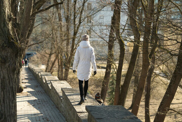 A woman in a white jacket walks on concrete steps with a child in a park. spring in Estonia 2021. Sunny day