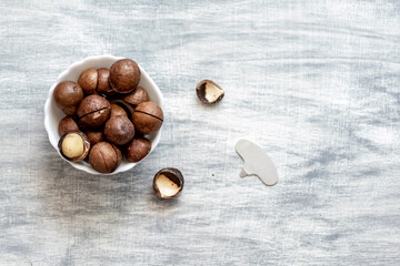 small white bowl with macadamia nuts, next to a nut opener and an open nut