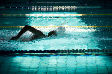 Swimmer swims freestyle in the pool in beautiful sunlight - obrazy, fototapety, plakaty