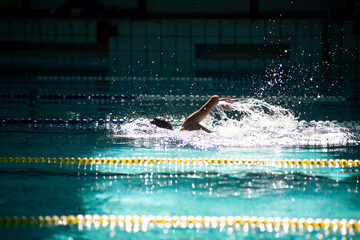 Swimmer swims freestyle in the pool in beautiful sunlight