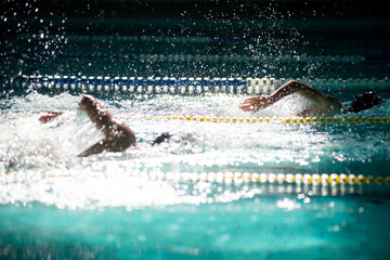 Race of two freestyle swimmers in the pool in beautiful sunlight 
