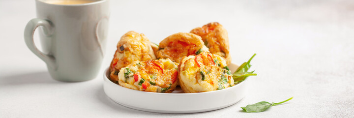 Egg muffins ( bites) and spinach leaves  in a plate on a gray background