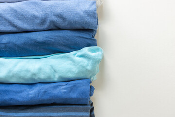 various shades of blue tee or t-shirts or undershirts rolled and folded on white