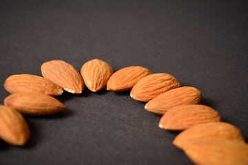 Raw almond nuts on dark background. Scattered almonds. Food ingredients. Kitchen still life. Copy space image. Creative food concept
