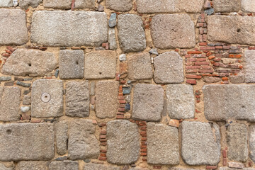 Architecture textures, detailed and rustic of irregular paired masonry granite mix with ceramic clay brick, traditional spanish granite wall
