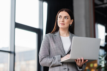 Businesswoman in formal wear holding laptop in office