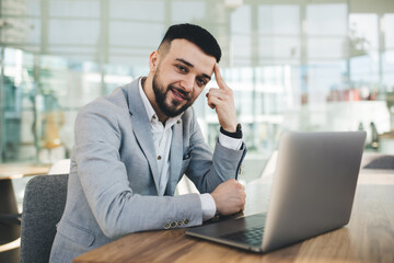 Content businessman working on laptop and touching forehead