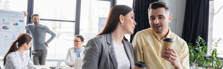 Smiling businessman with coffee to go talking to colleague, banner
