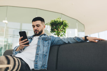 Adult hipster browsing smartphone while sitting on bench