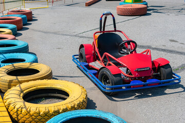 Outdoor karting and a red electric sports car on a race track equipped with protective curbs made of old tires