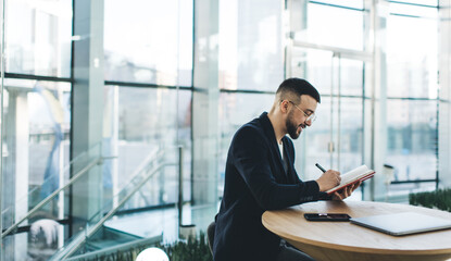 Smiling man writing thoughts in planner