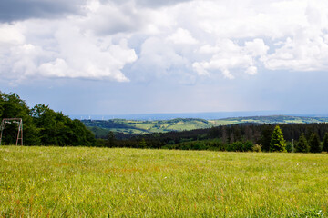 Landscape on Hoherodskopf, volcano region in Hesse, Germany. On cloudy sunny warm summer day, meadows, hills, fields and forests.