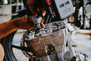 Mechanic is assembling the cylinder head of a motorcycle engine.