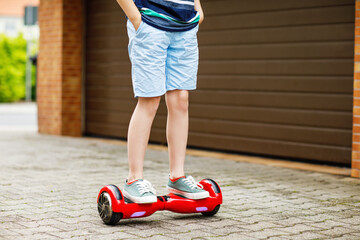 Close-up of kid boy on hover board. Child driving modern balance hoverboard. Excercise and sports...