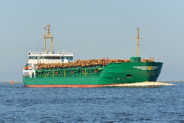 Large green cargo ship, 100 meters length, with firewood sailing in the Baltic sea. Freight...