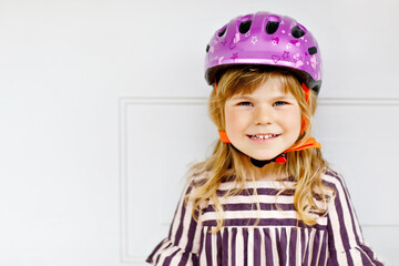 Portrait of happy smiling preschool girl with bycicle helmet on head. Cute toddler child. Safe bike driving with children concept. Safety helmet for kids